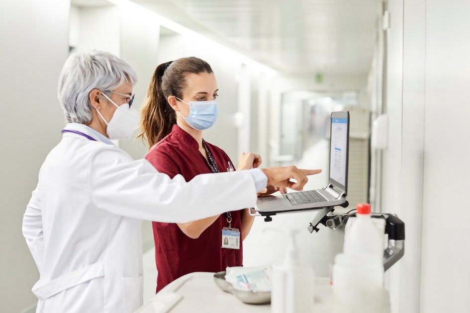 Doctor and nurse pointing at a laptop, wearing masks