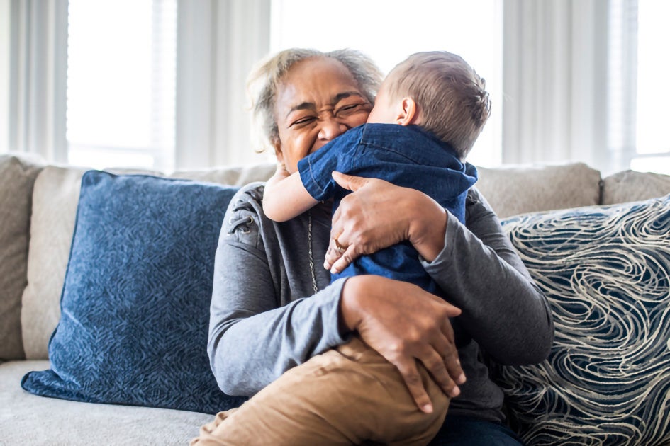 Grandmother hugging grandson while sitting on the couch